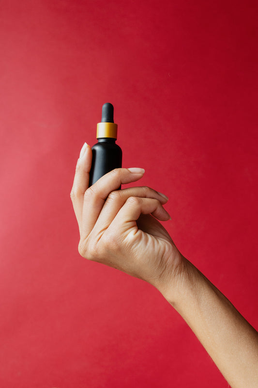 Hand holding a dropper bottle of beard oil