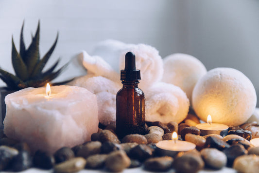 Body oil bottle beside lit candles
