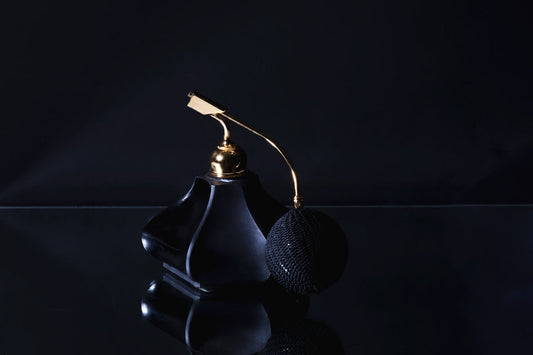 Black glass oud perfume flacon on a dark surface