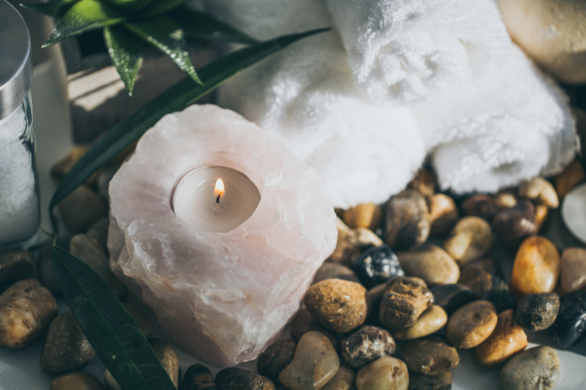 Small travel candle beside smooth stones